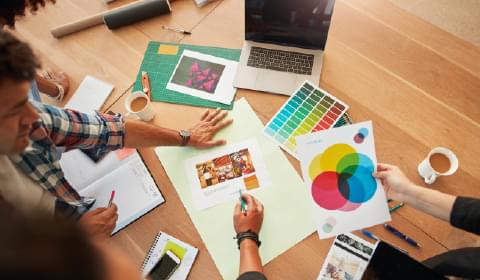 Image of people looking at colour palettes and plans at a table to portray the advertising industry