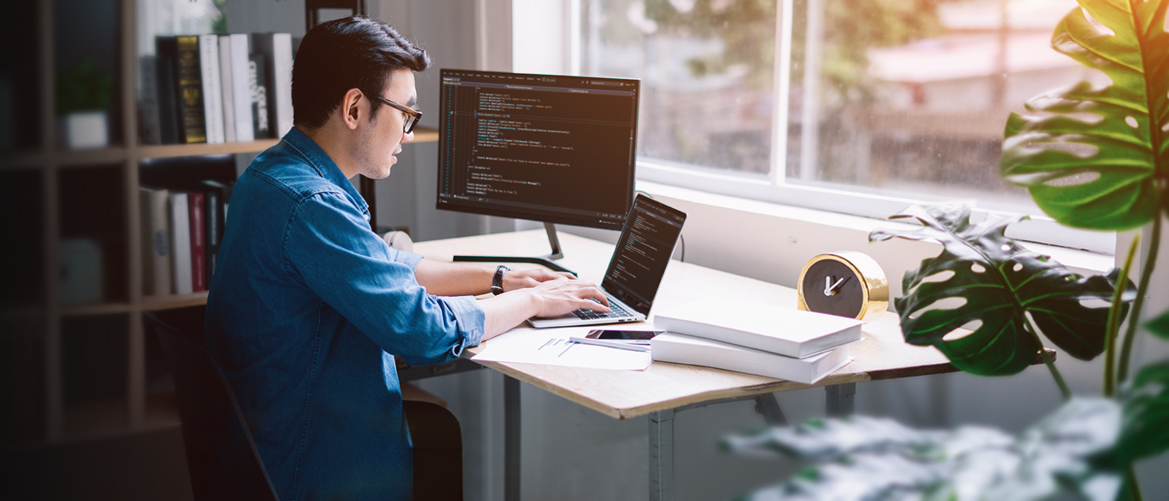 Asian American male professional coder writing a Python program on his laptop in office